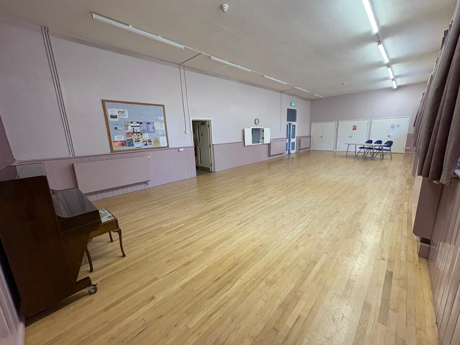 Photo of main hall showing doorways, kitchen hatch and piano